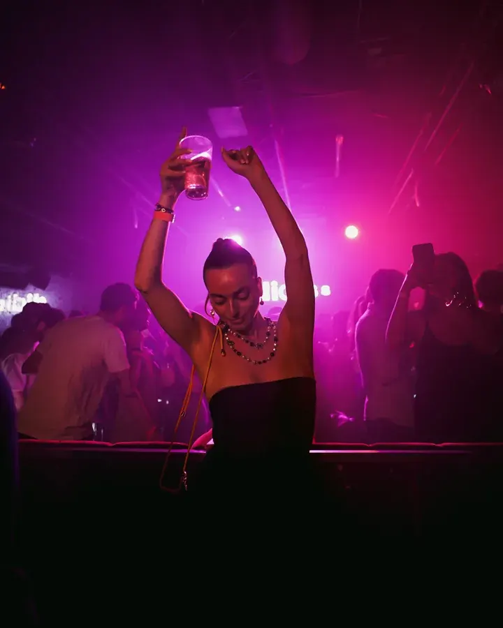 Guest raising a glass in pink light